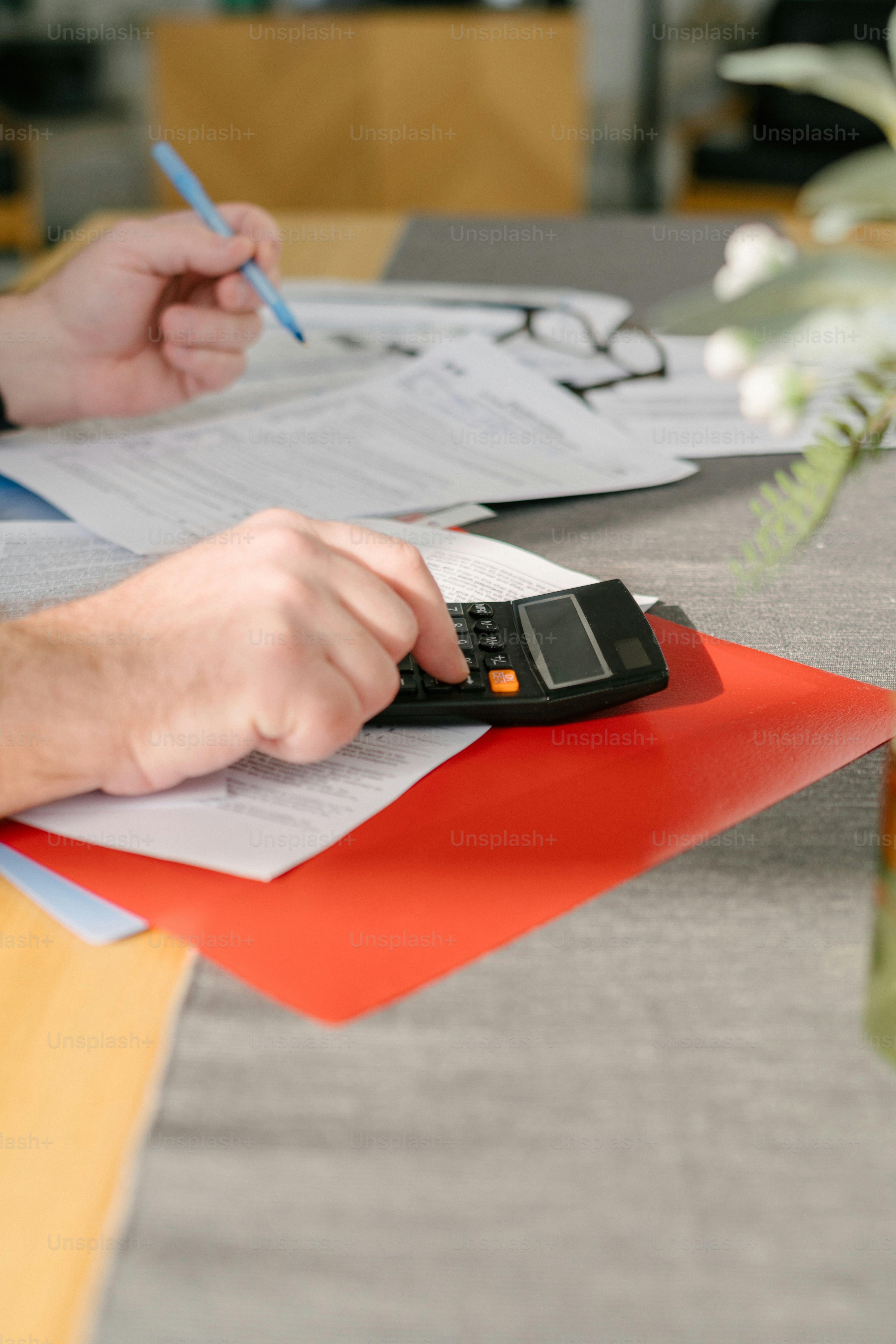 Eine Person, die mit einem Taschenrechner an einem Tisch sitzt