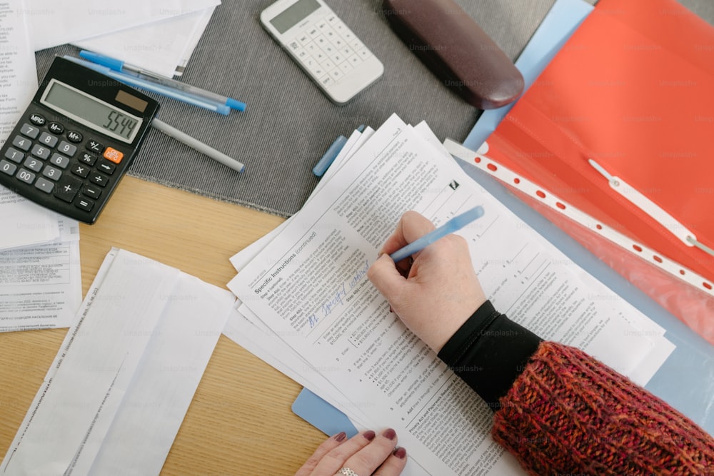 a person sitting at a desk with papers and a calculator