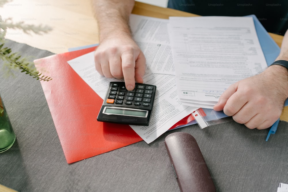 a man is using a calculator on top of papers