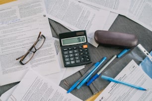 a calculator, pen, glasses, and a pair of eyeglasses