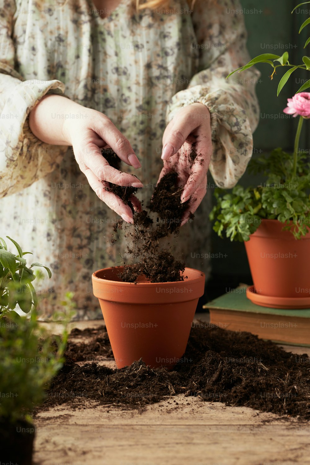 a woman is putting dirt in a potted plant