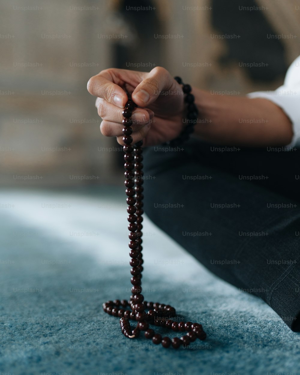 una persona seduta a terra con in mano un rosario