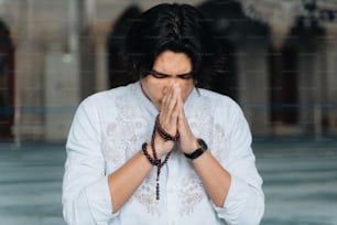 흰 셔츠를 입은 남자가 기도하고 있다