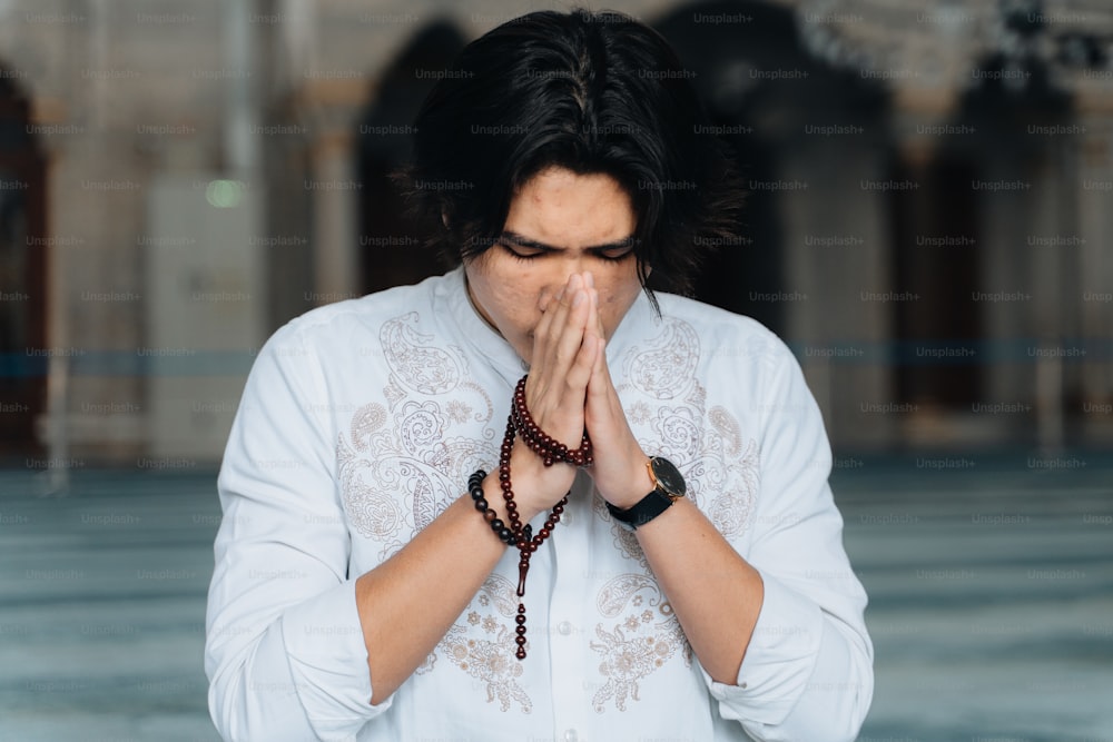 Un hombre con una camisa blanca está rezando
