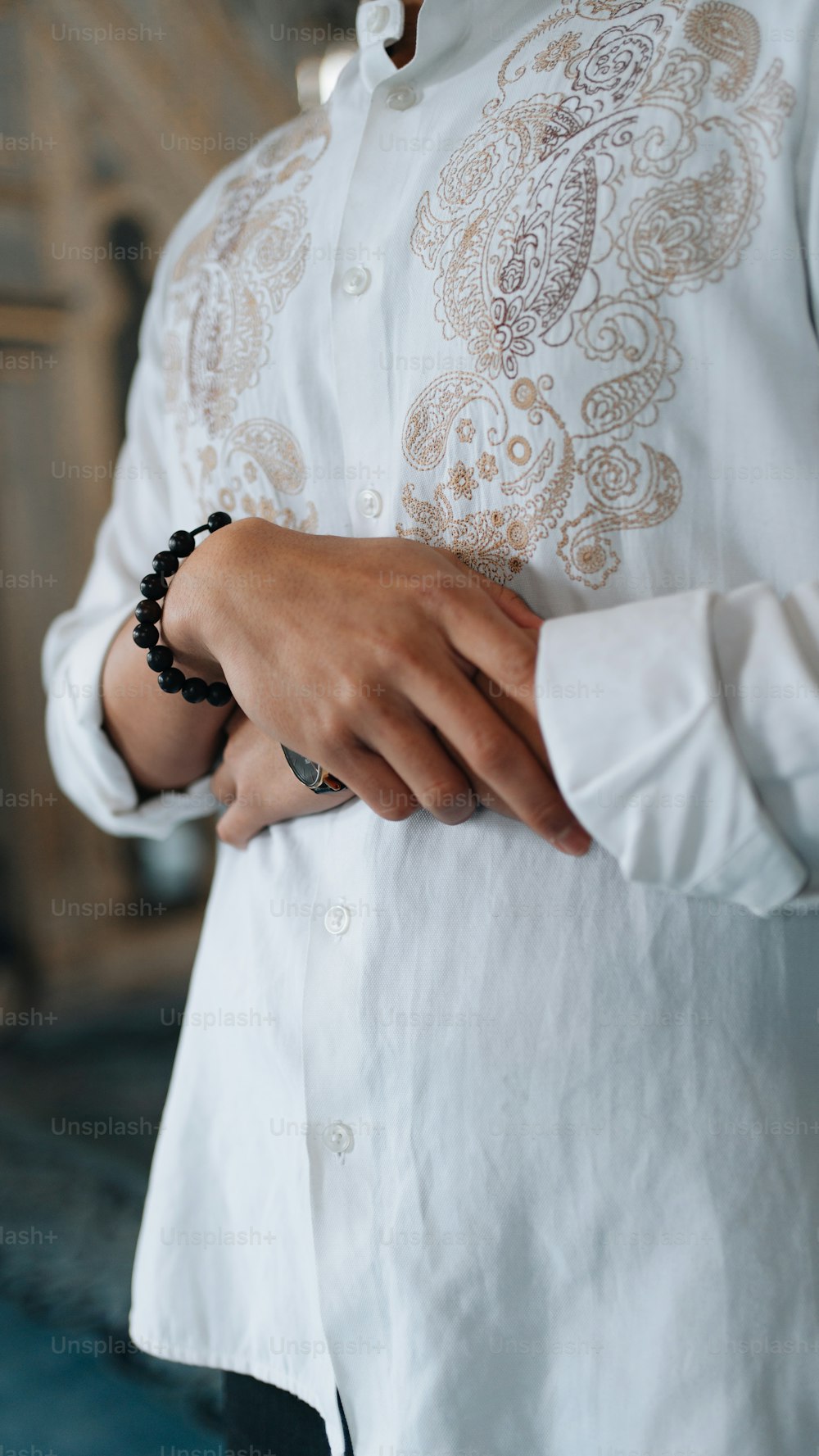 a person wearing a white shirt and a beaded bracelet