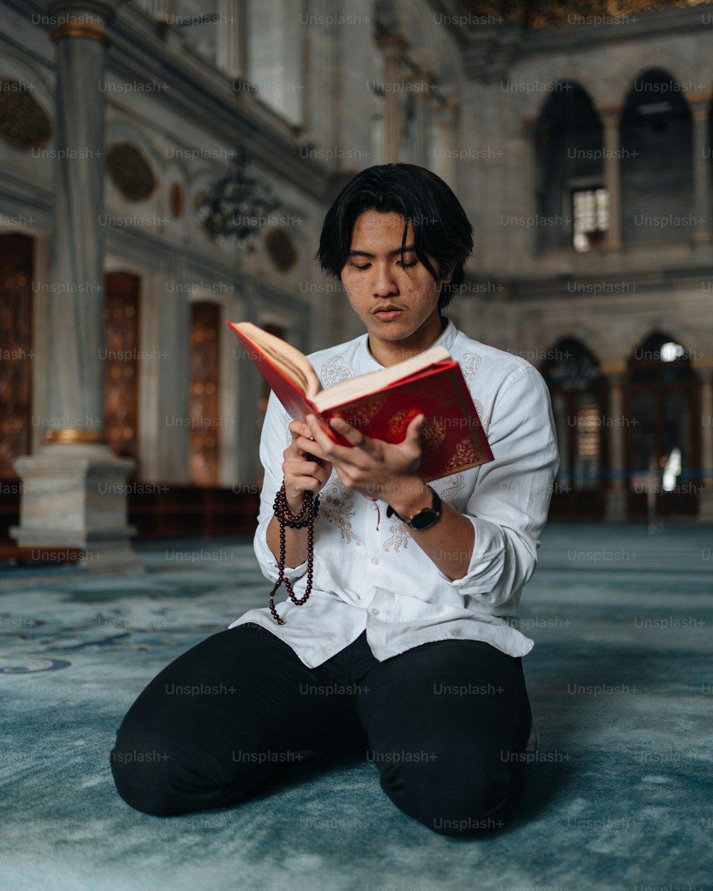 a man sitting on the floor reading a book