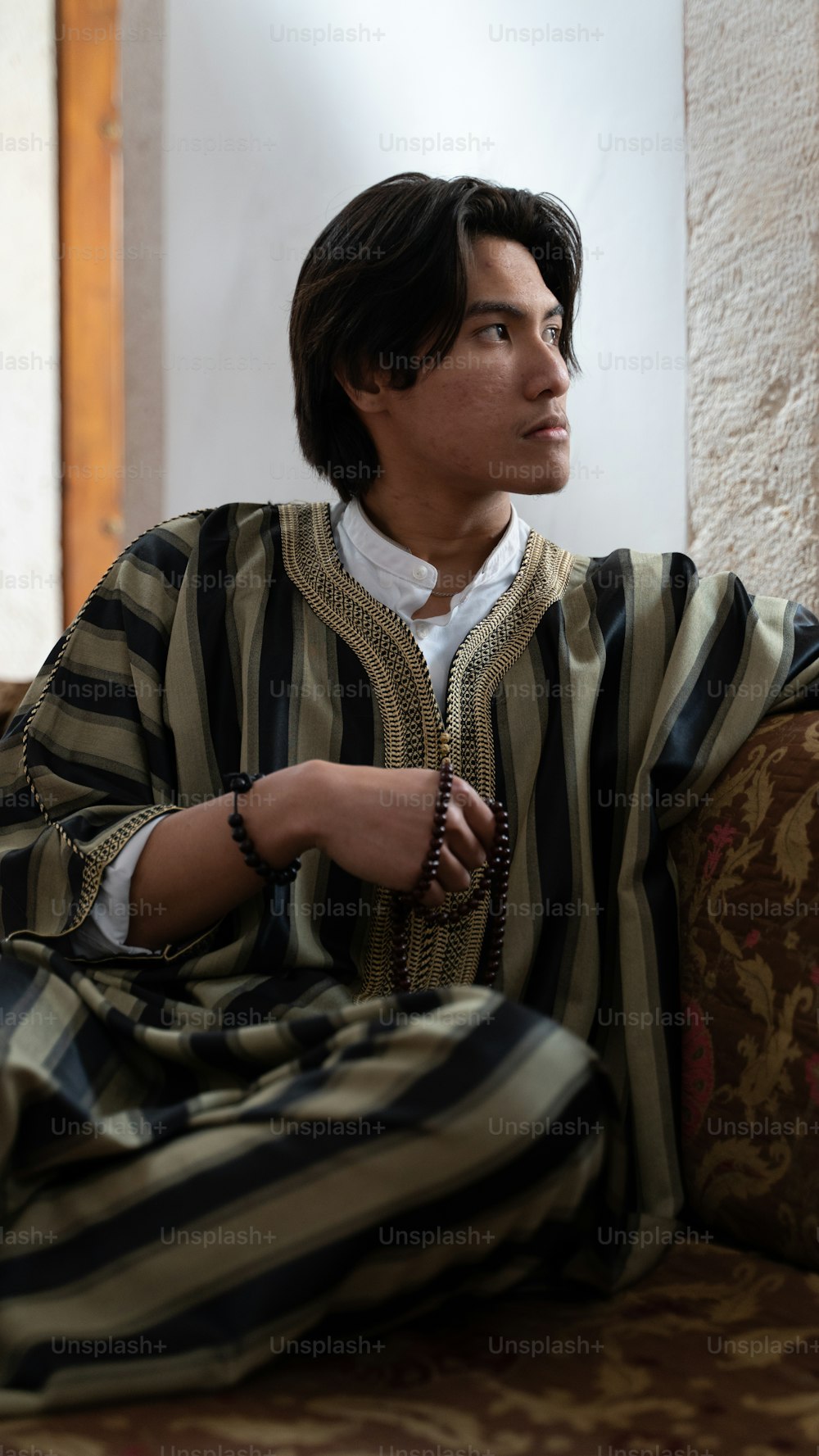a man sitting on a couch wearing a striped robe