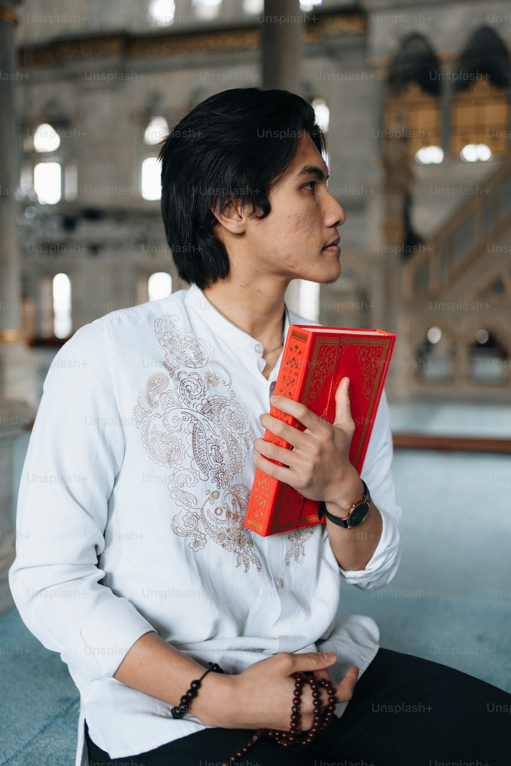 a man in a white shirt holding a red book