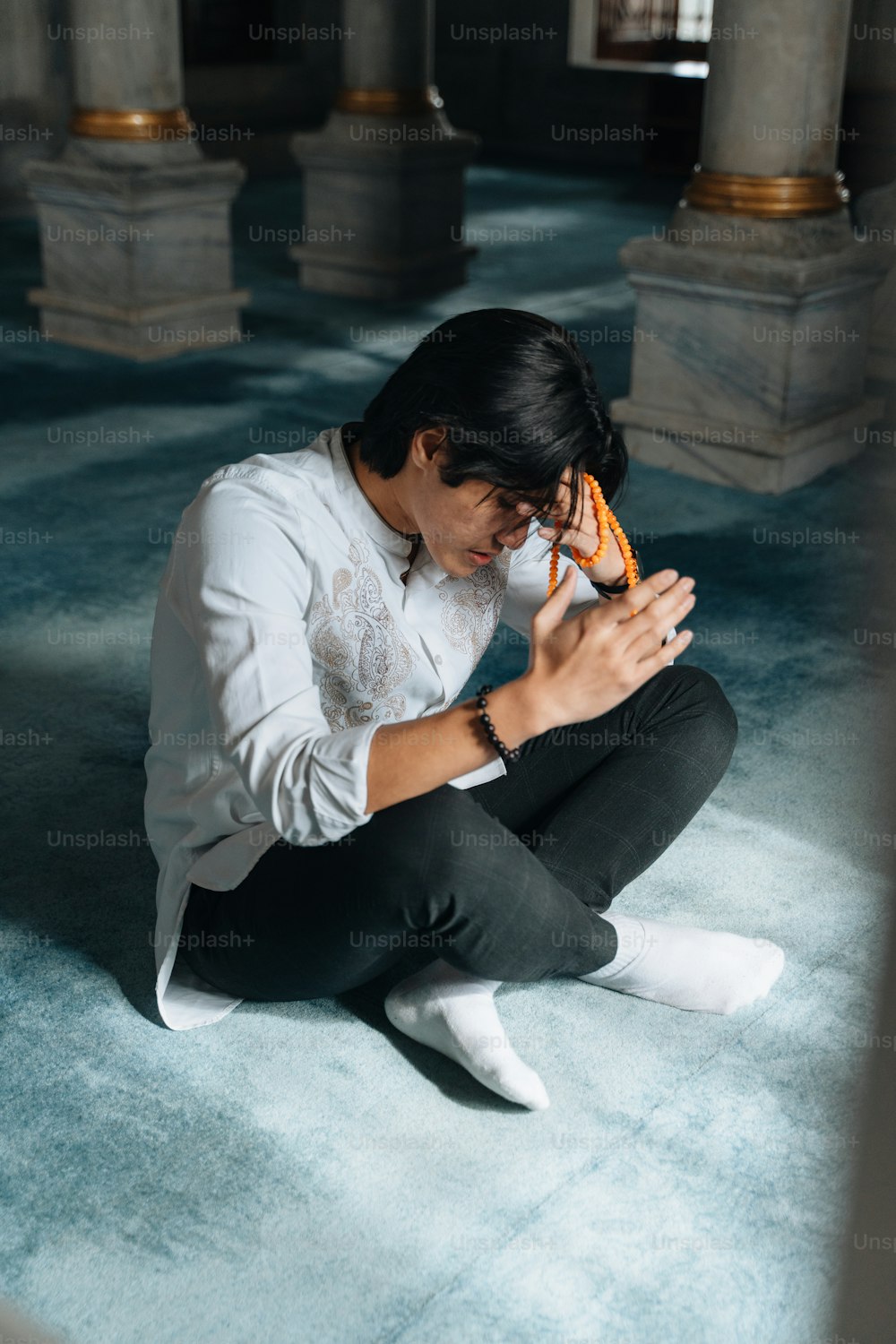 Un uomo seduto sul pavimento con in mano un telefono cellulare