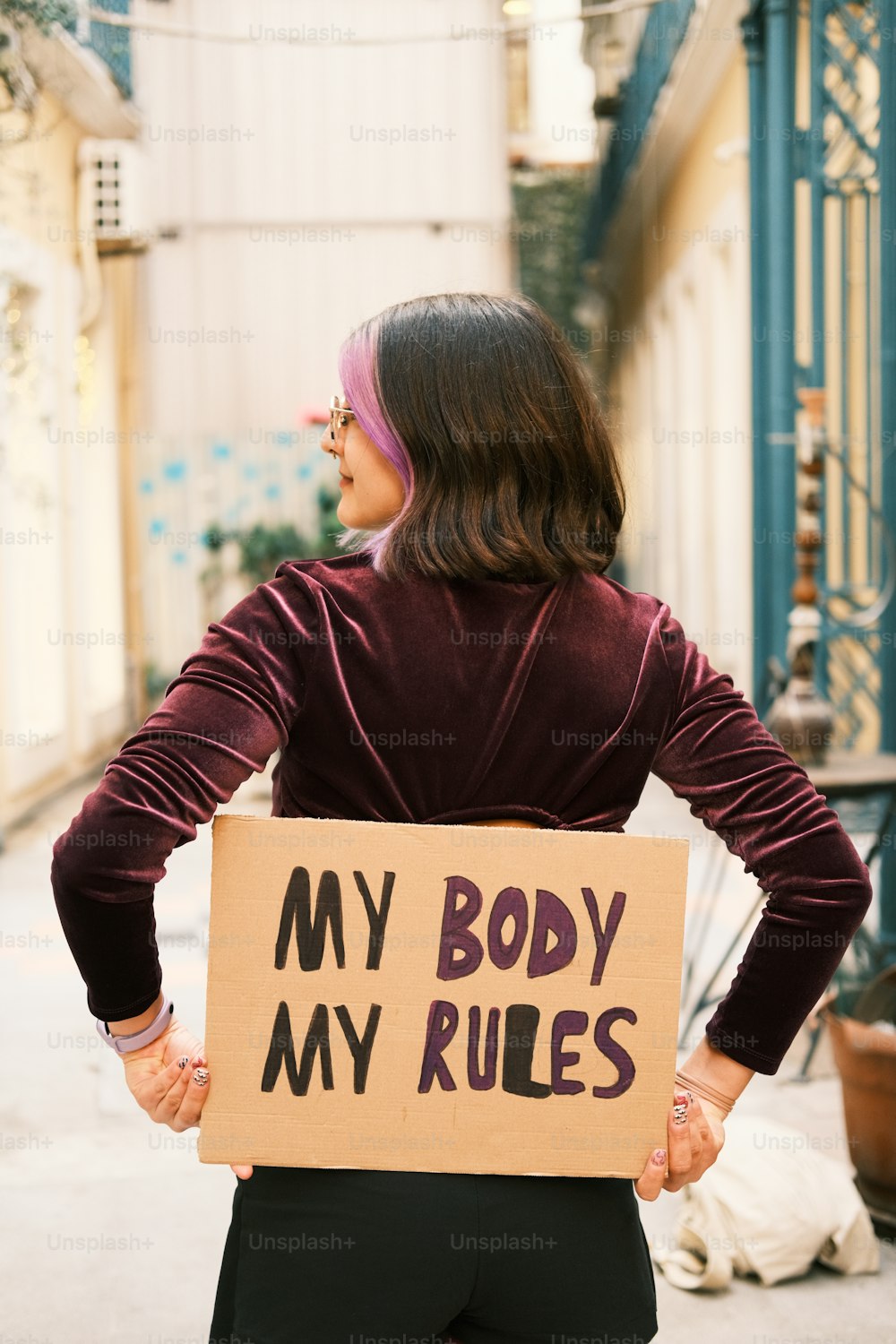a woman holding a cardboard sign that says, my body my rules