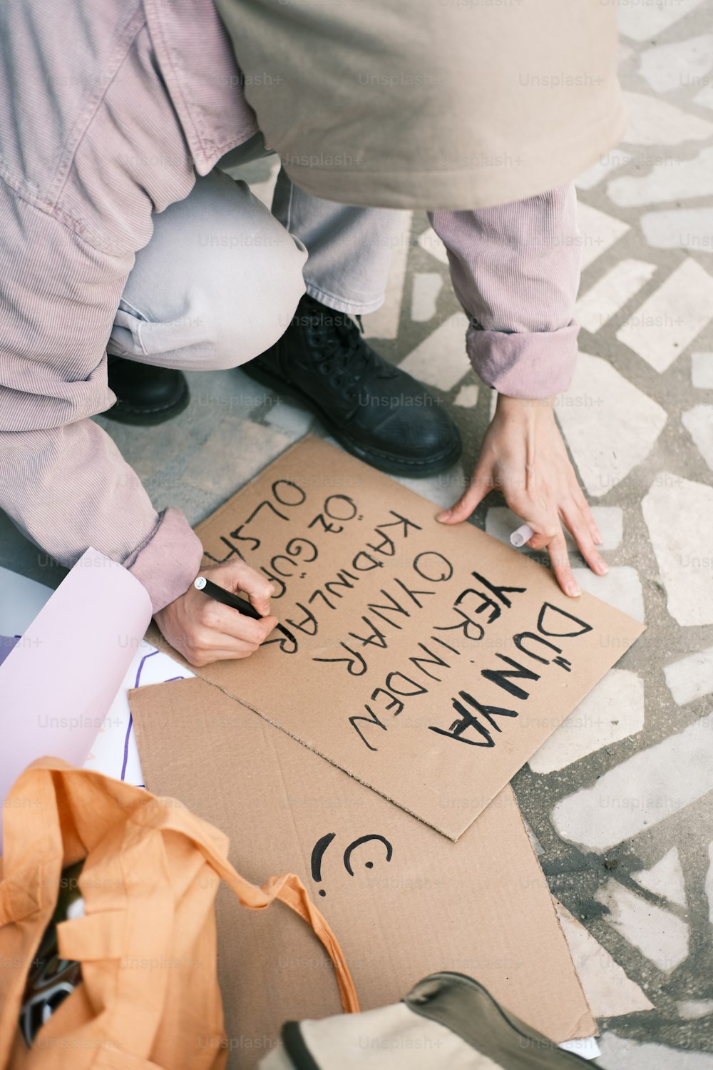 a man is writing on a cardboard sign