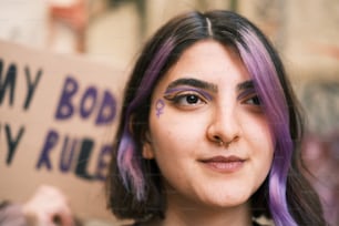 una donna con i capelli viola che tiene un segno