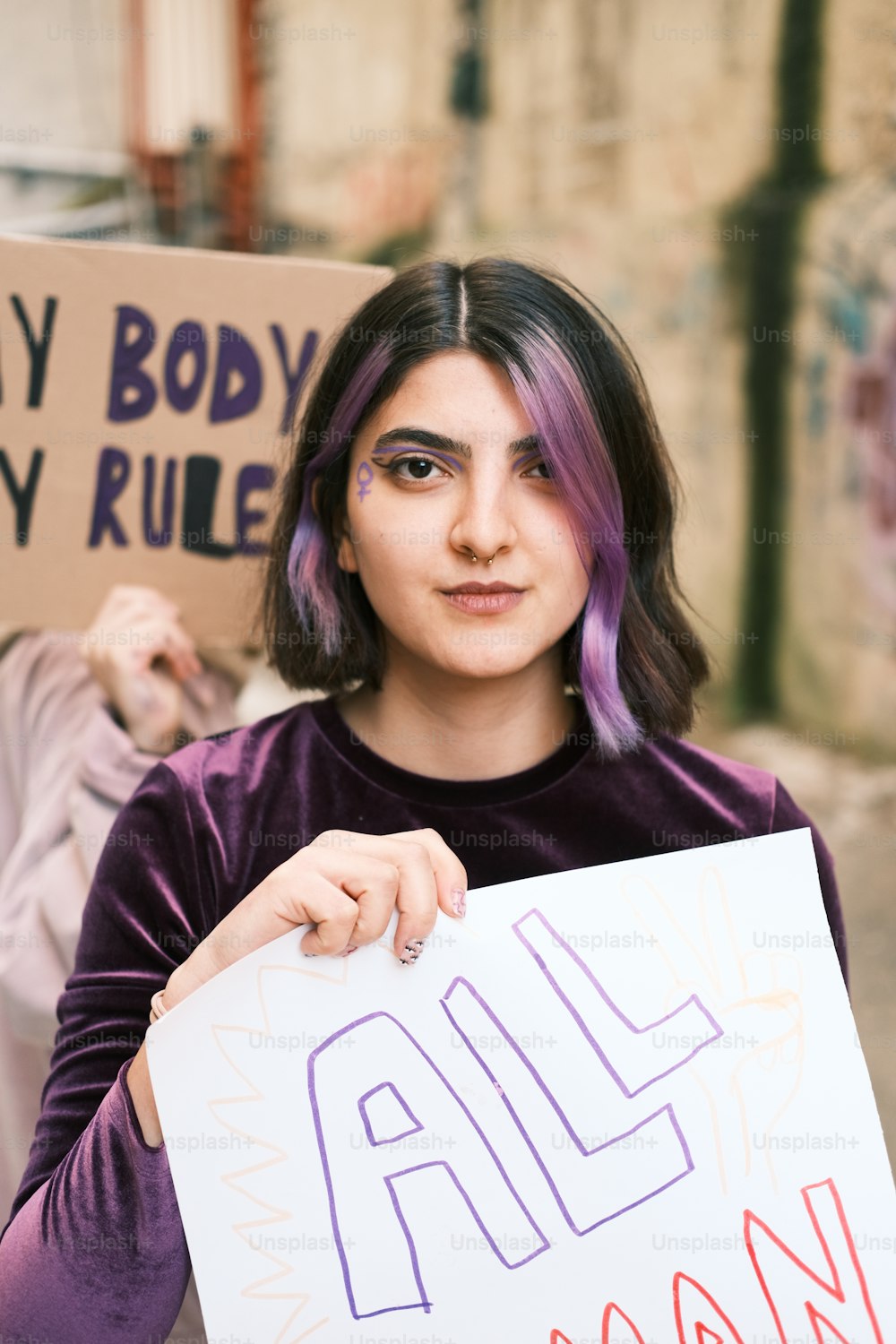 a woman with purple hair holding a sign