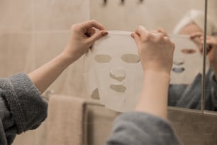 una persona che tiene un foglio di carta con una maschera facciale