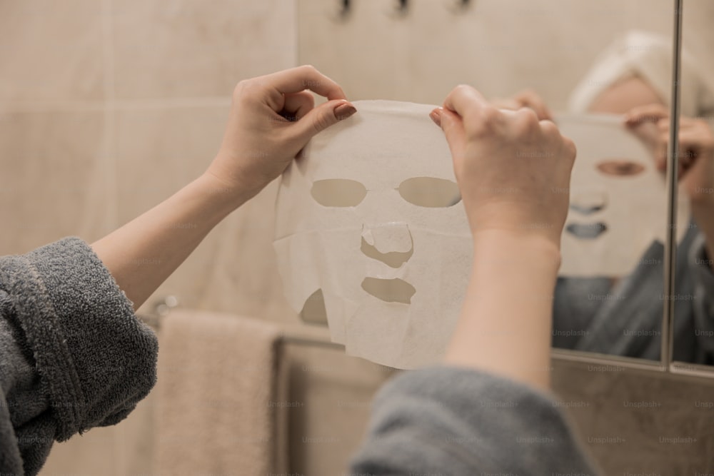 uma pessoa segurando uma folha de papel com uma máscara facial