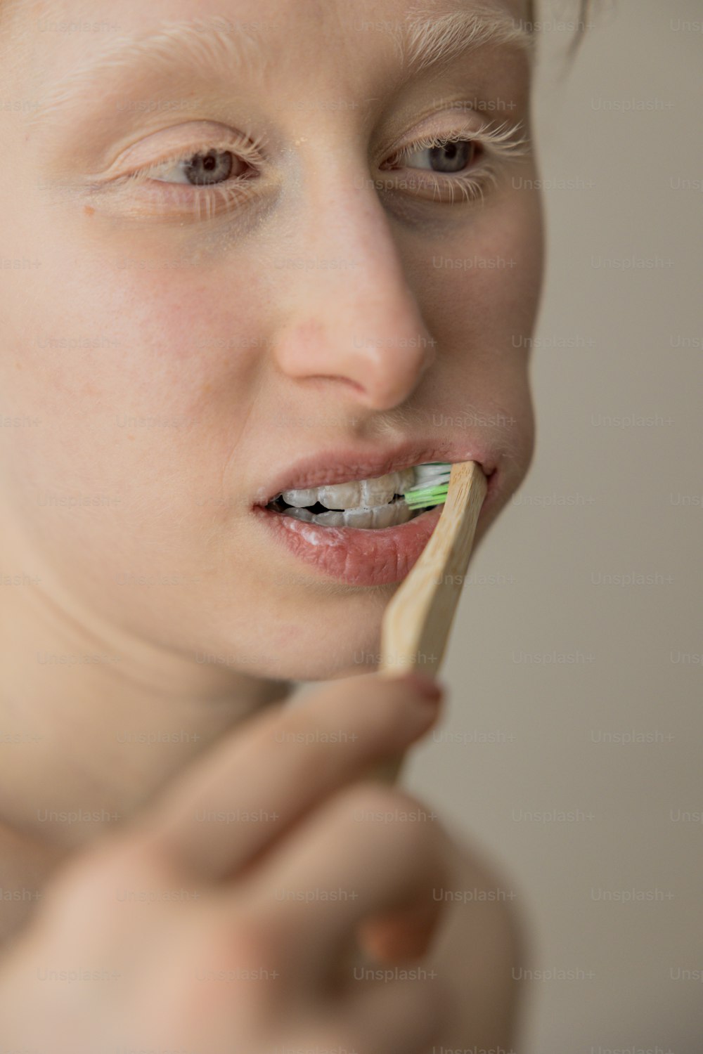 a woman brushing her teeth with a toothbrush