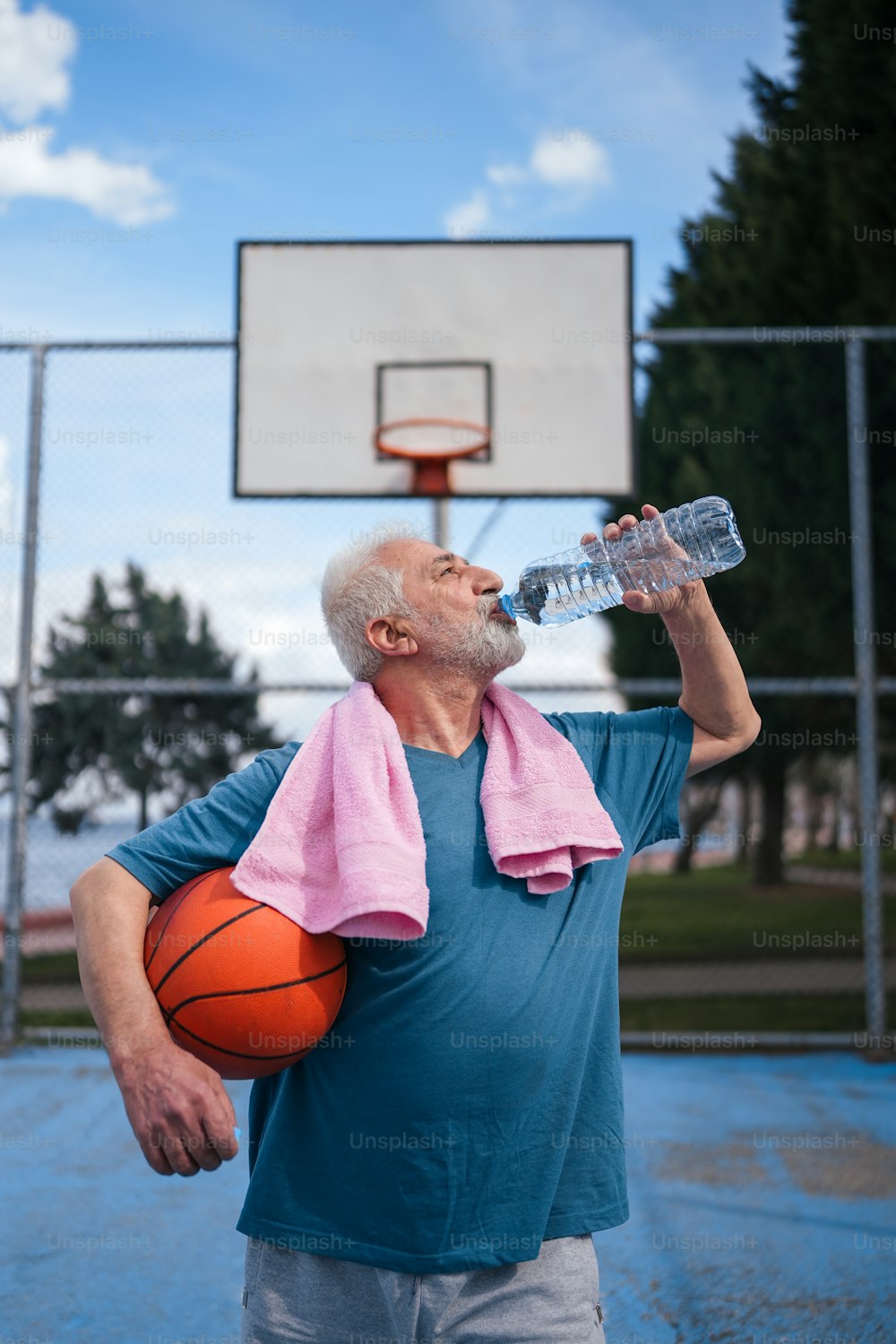 Ein Mann mit einem Handtuch auf den Schultern trinkt Wasser aus einer Wasserflasche