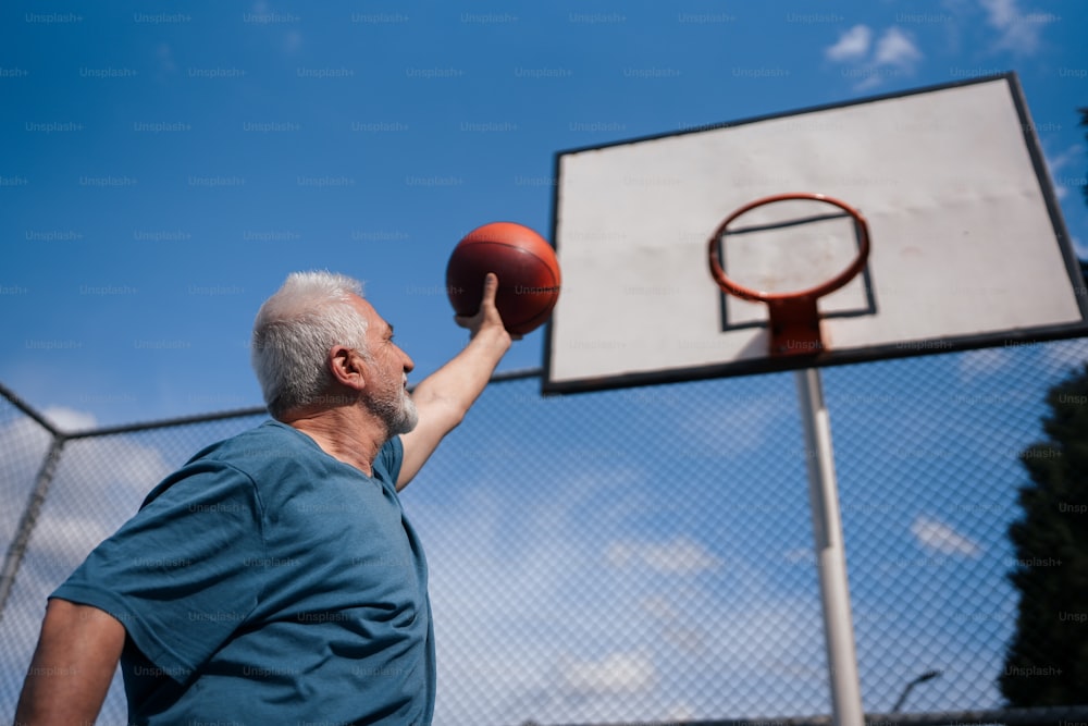 Un uomo che tiene un pallone da basket fino a un canestro da basket