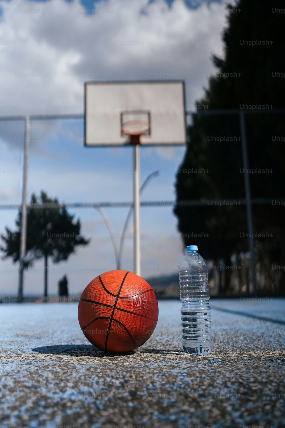 una pelota de baloncesto y una botella de agua sentadas en una cancha de baloncesto