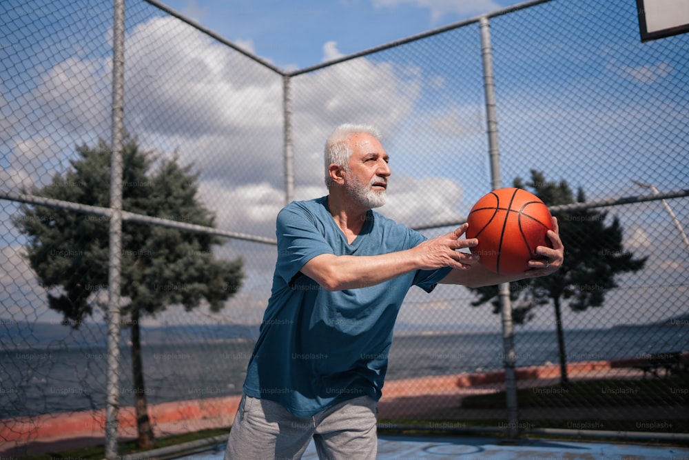 a man holding a basketball in front of a fence