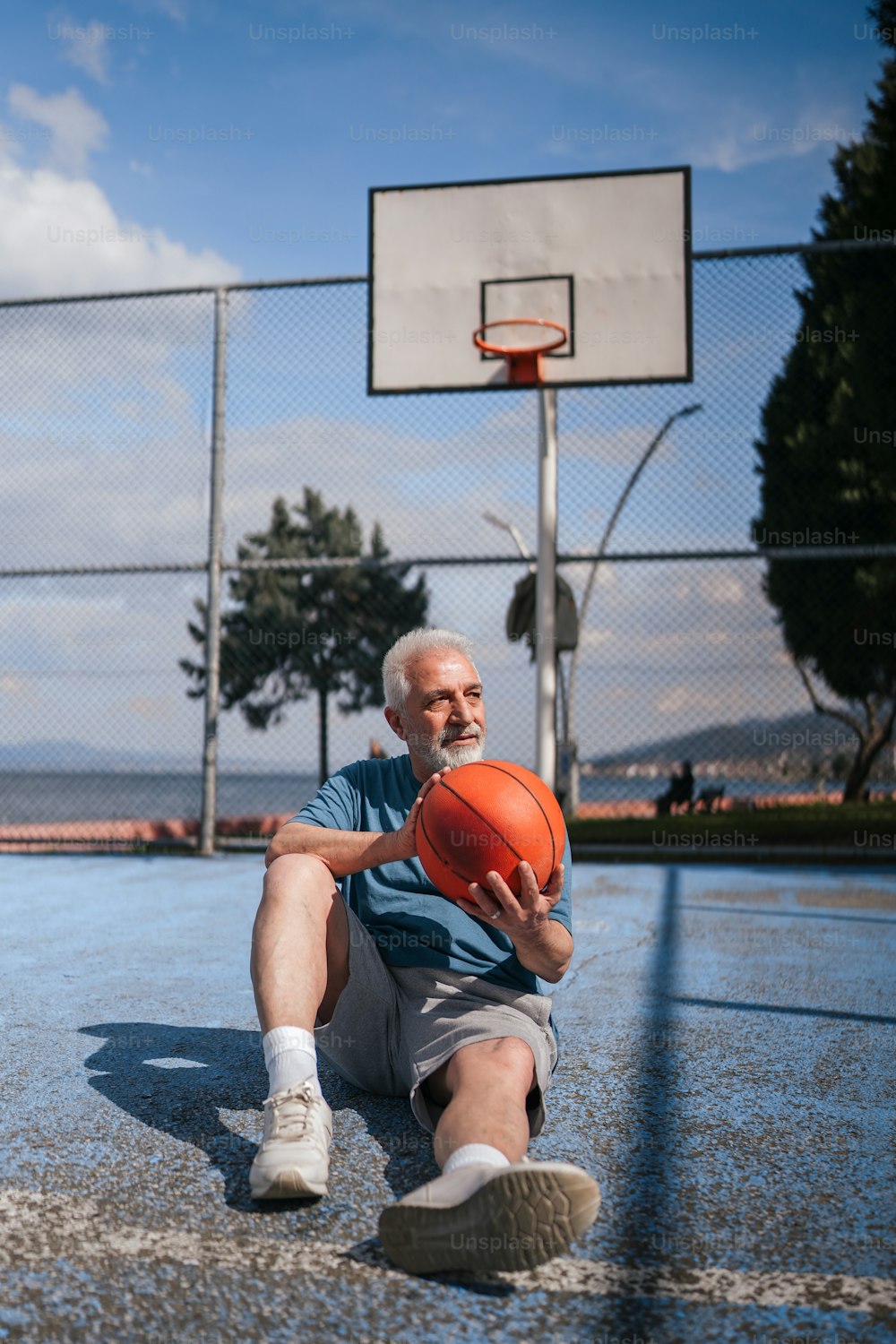 バスケットボールコートに座ってバスケットボールを持っている男性