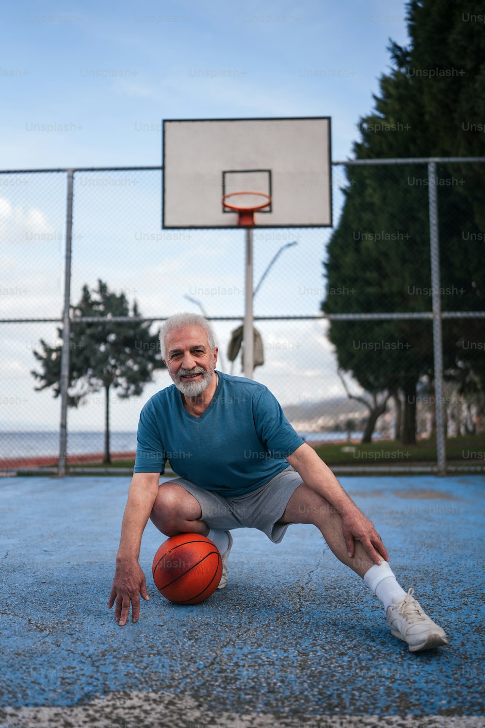 Un hombre arrodillado con una pelota de baloncesto en la mano