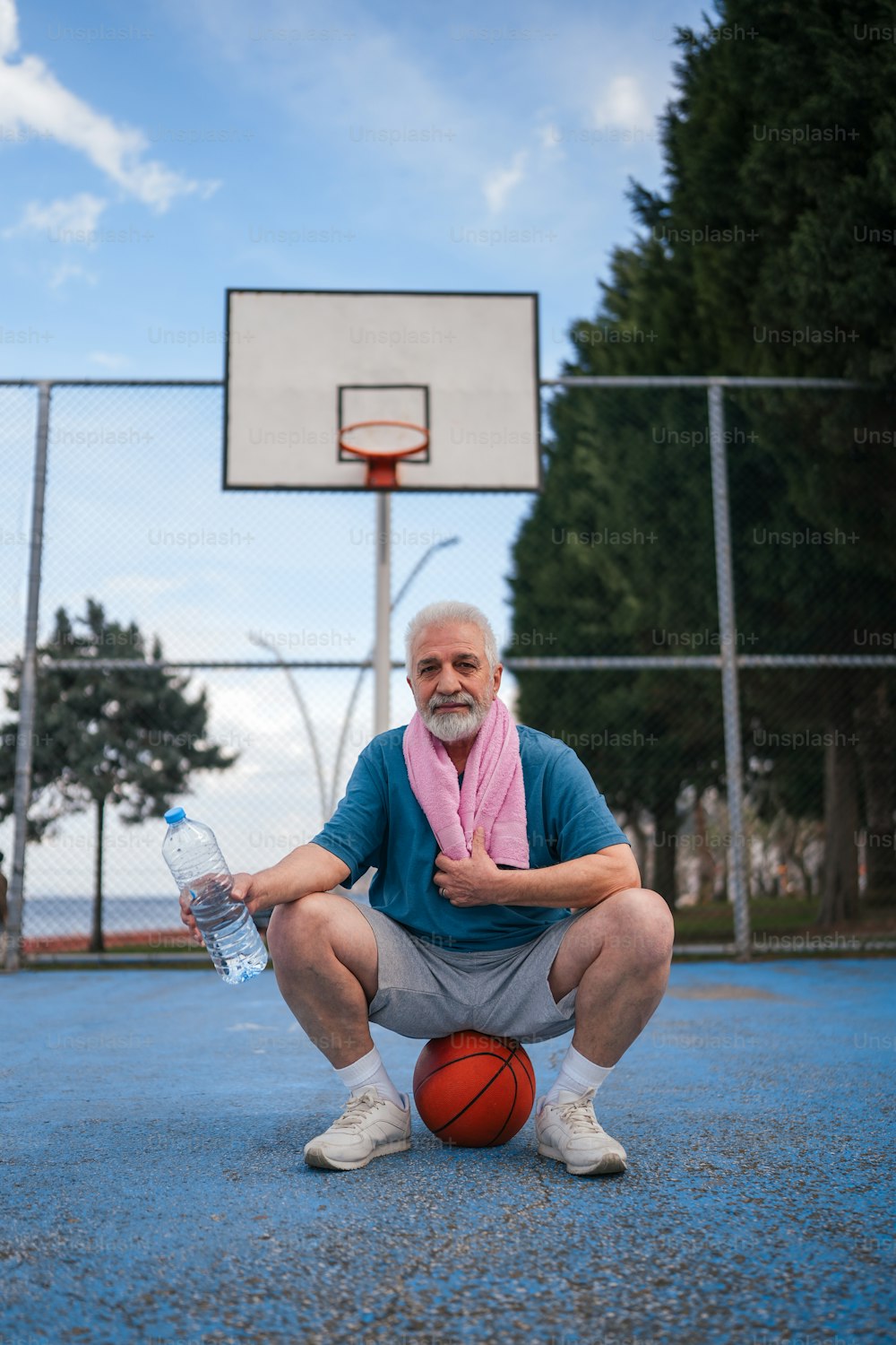 バスケットボールコートに座って水筒を持つ男性