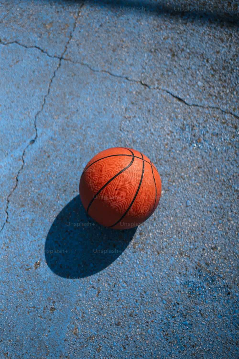 a basketball laying on the ground with a shadow