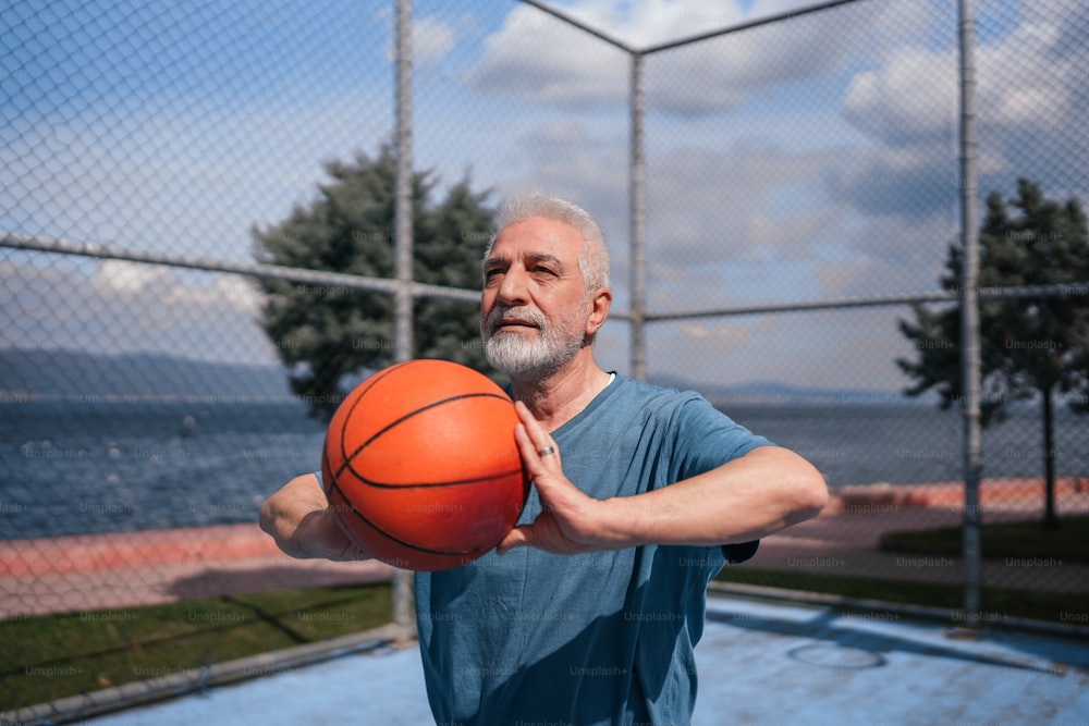 フェンス��の前でバスケットボールを持つ男
