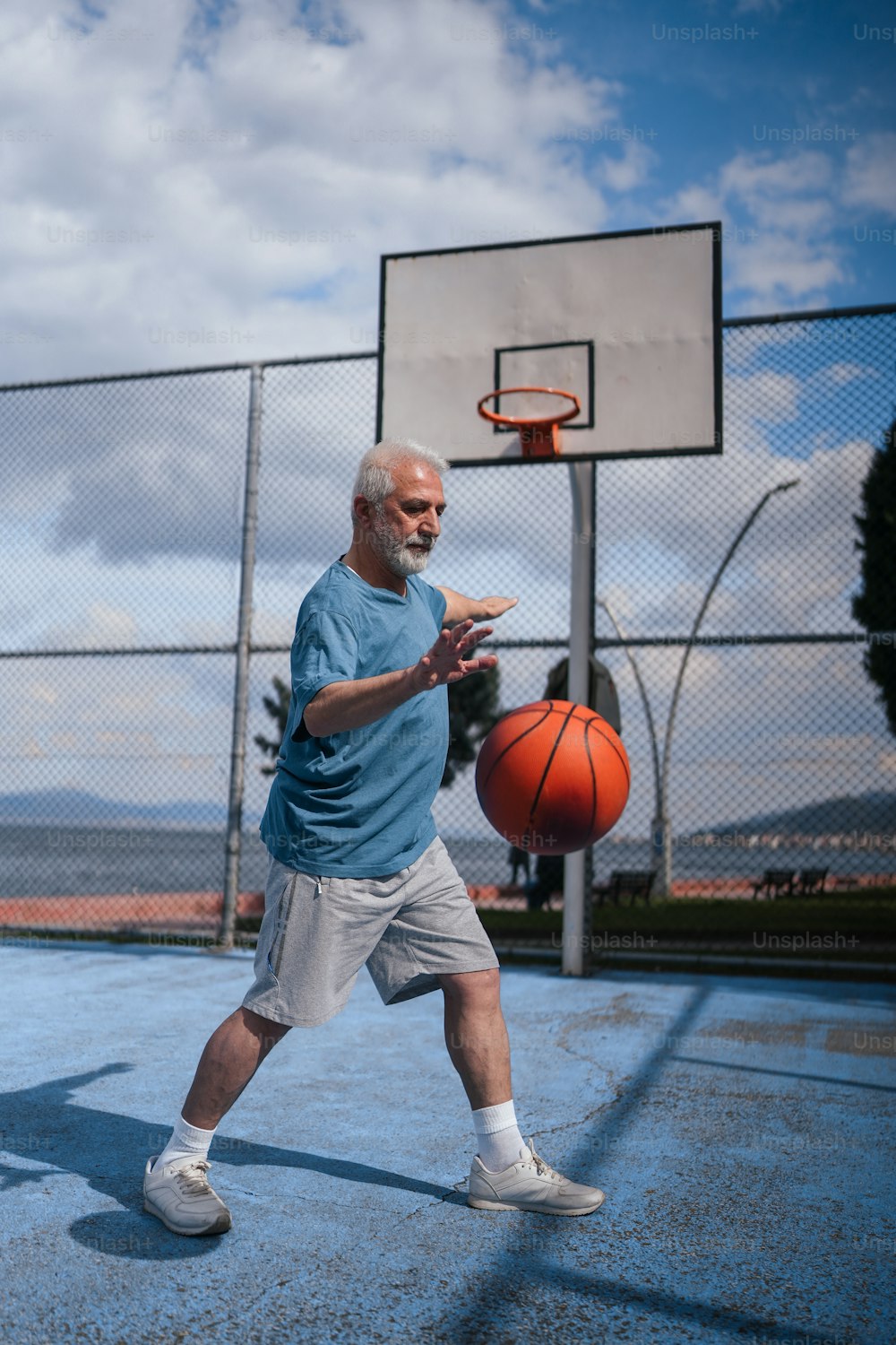 �年配の男性がコートでバスケットボールをしている