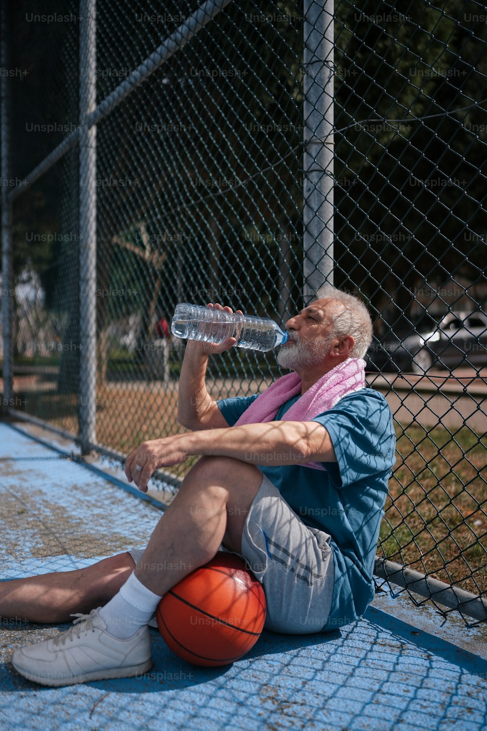 a man sitting on the ground drinking water from a bottle