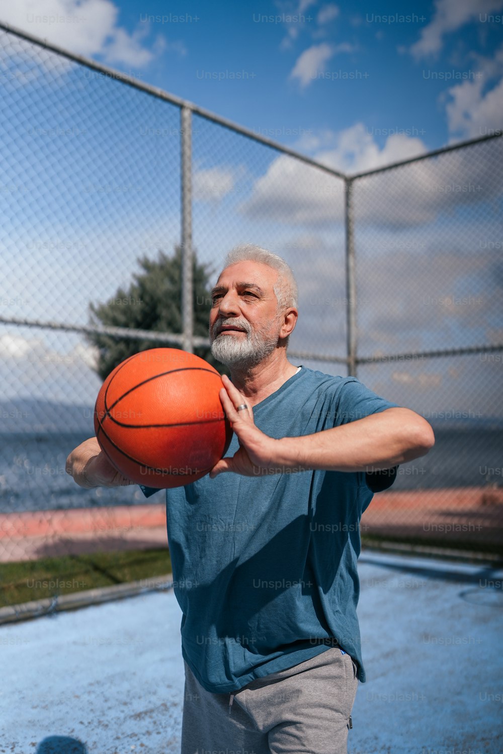 a man holding a basketball in front of a fence