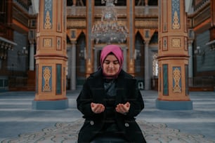 a woman in a black coat and a pink head scarf