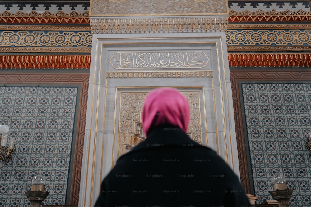 a woman in a pink headscarf standing in front of a door