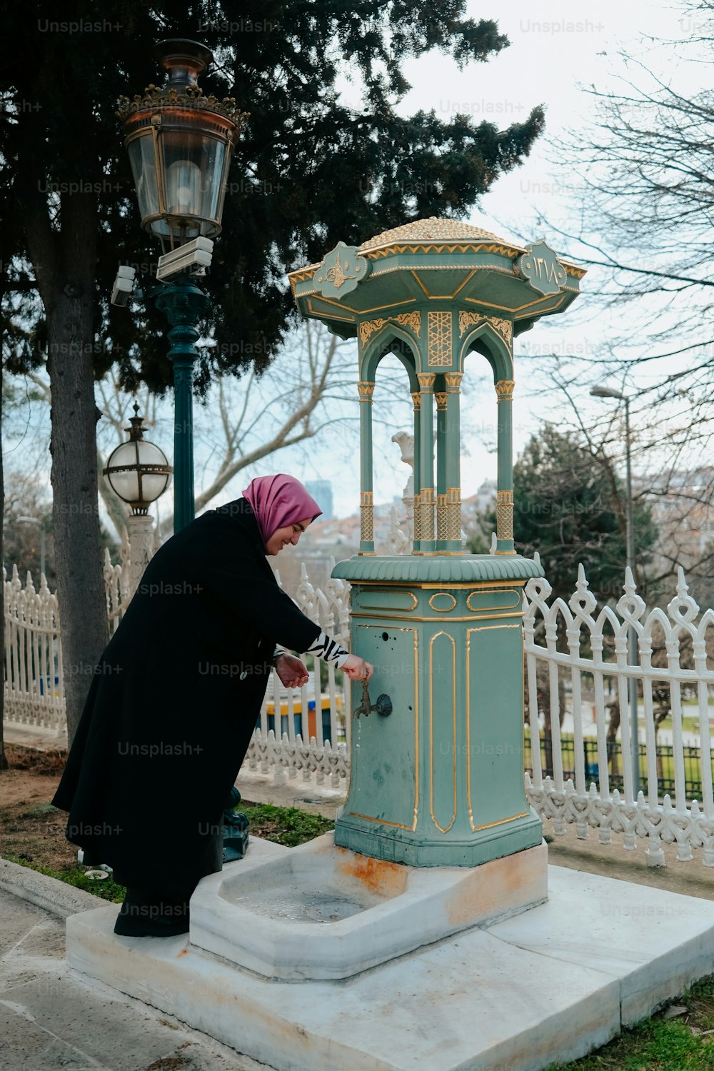a woman in a hijab is fixing a lamp post