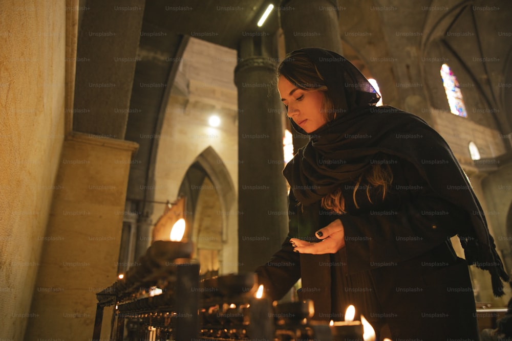 uma mulher em pé na frente de velas em uma igreja
