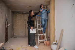a woman standing on a ladder next to a man