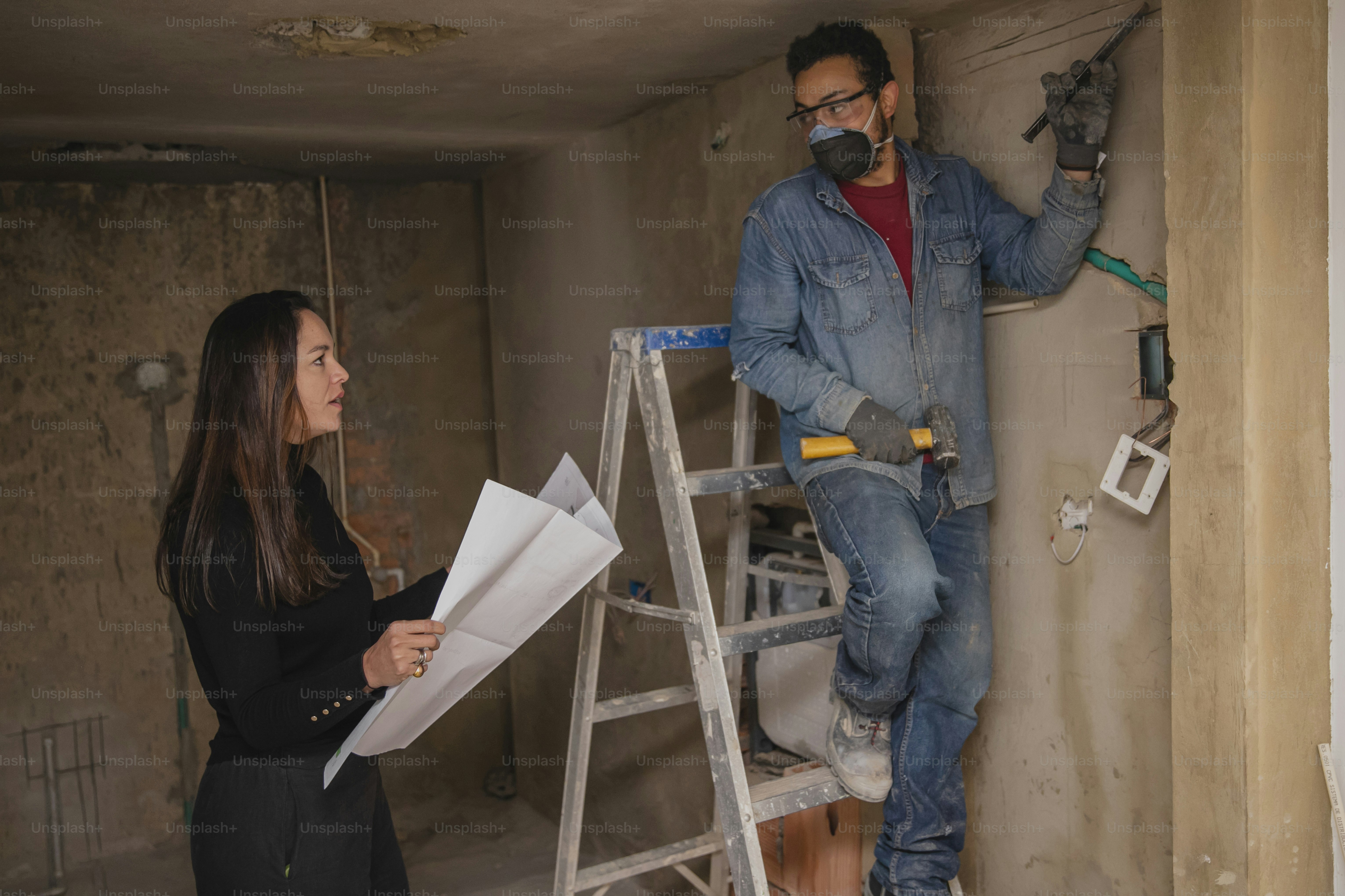 a man and a woman are working on a wall