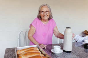 パンを持ってテーブルに座っている年配の女性