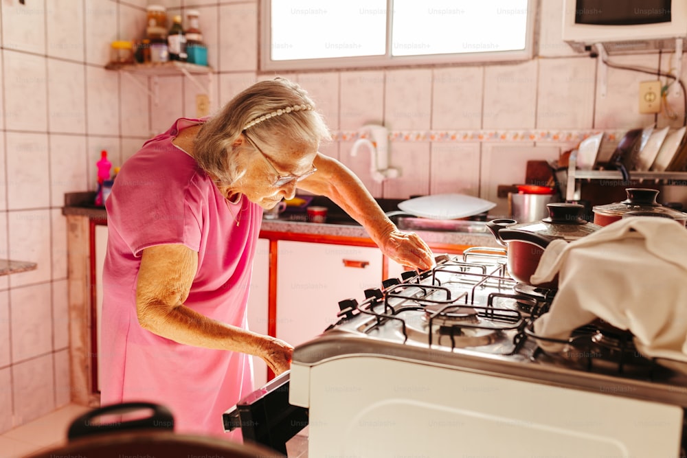 Una mujer con una camisa rosa está mirando una estufa