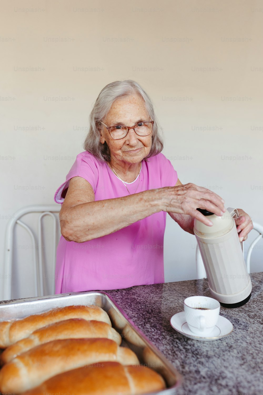 an older woman pouring a cup of coffee
