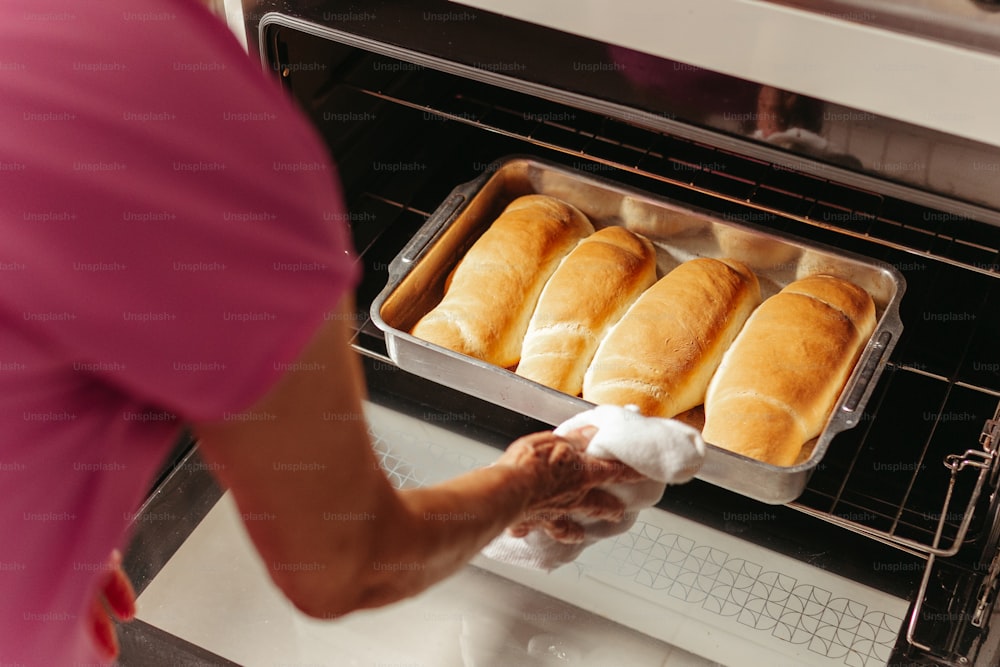 una persona sacando pan de un horno