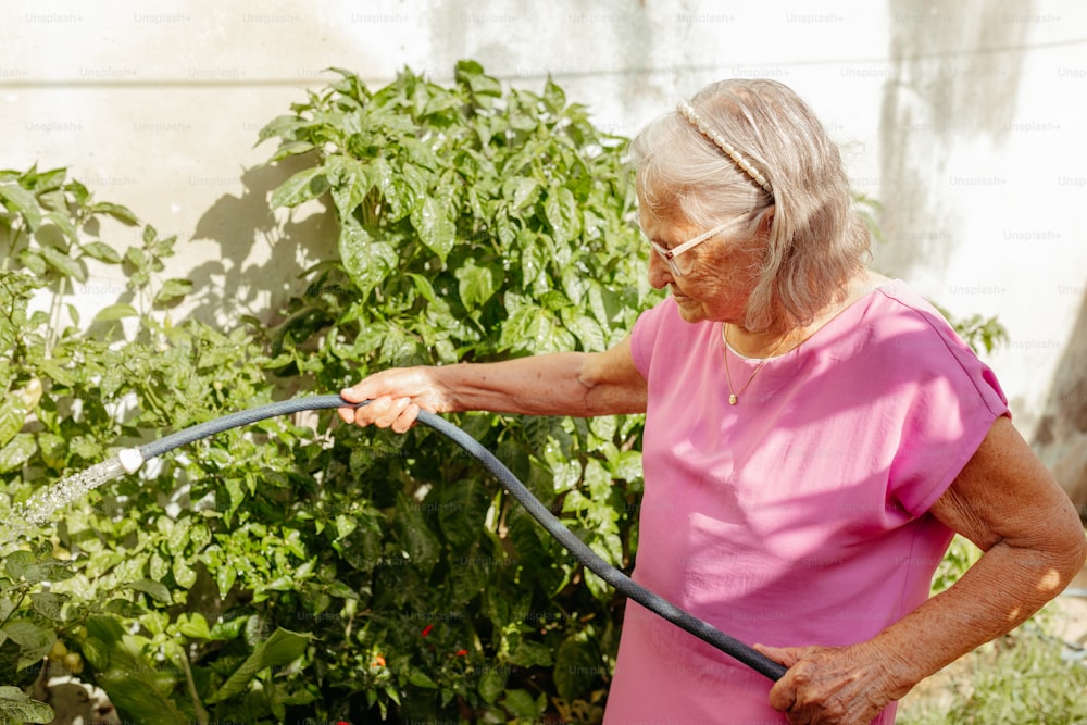 Eine Frau bewässert ihren Garten mit einem Schlauch