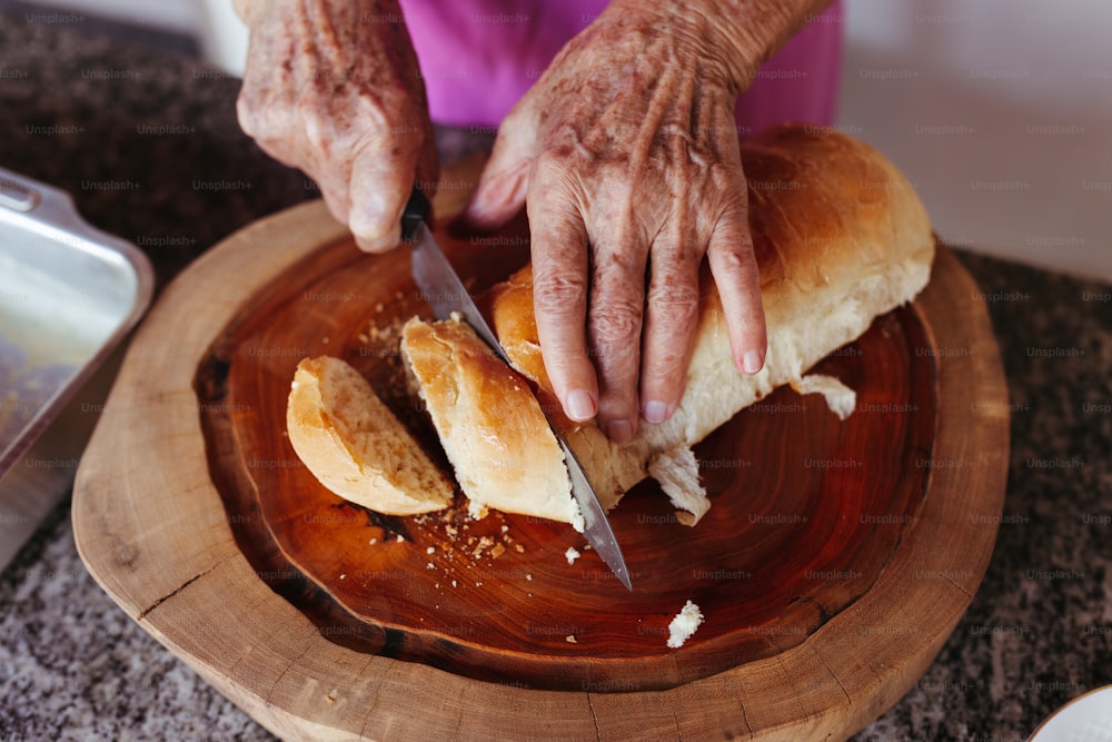 a person cutting bread with a knife on a wooden plate