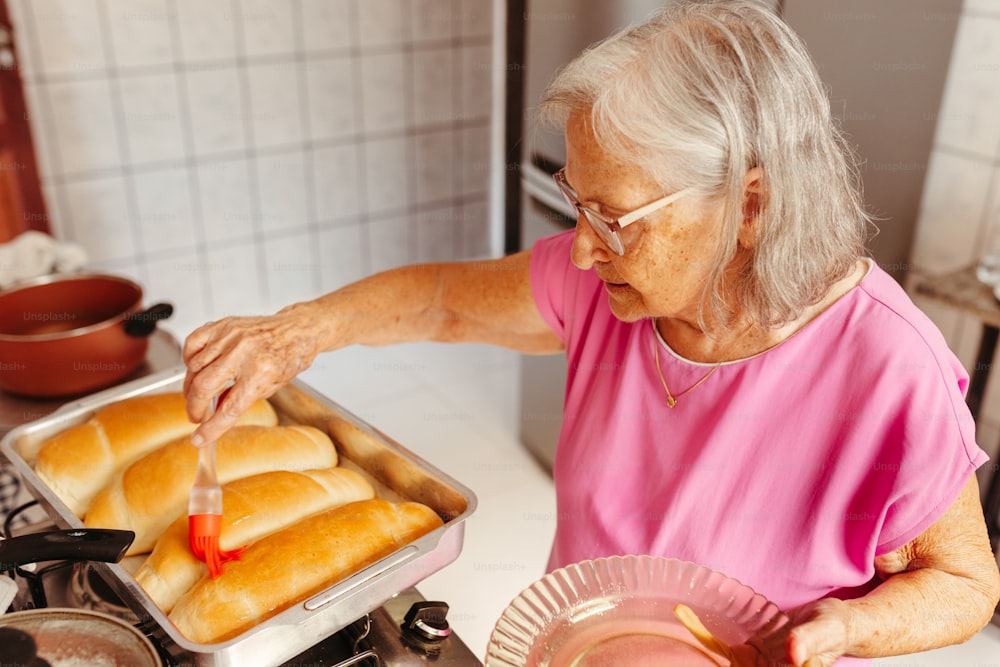 a woman in a pink shirt is putting bread into a pan