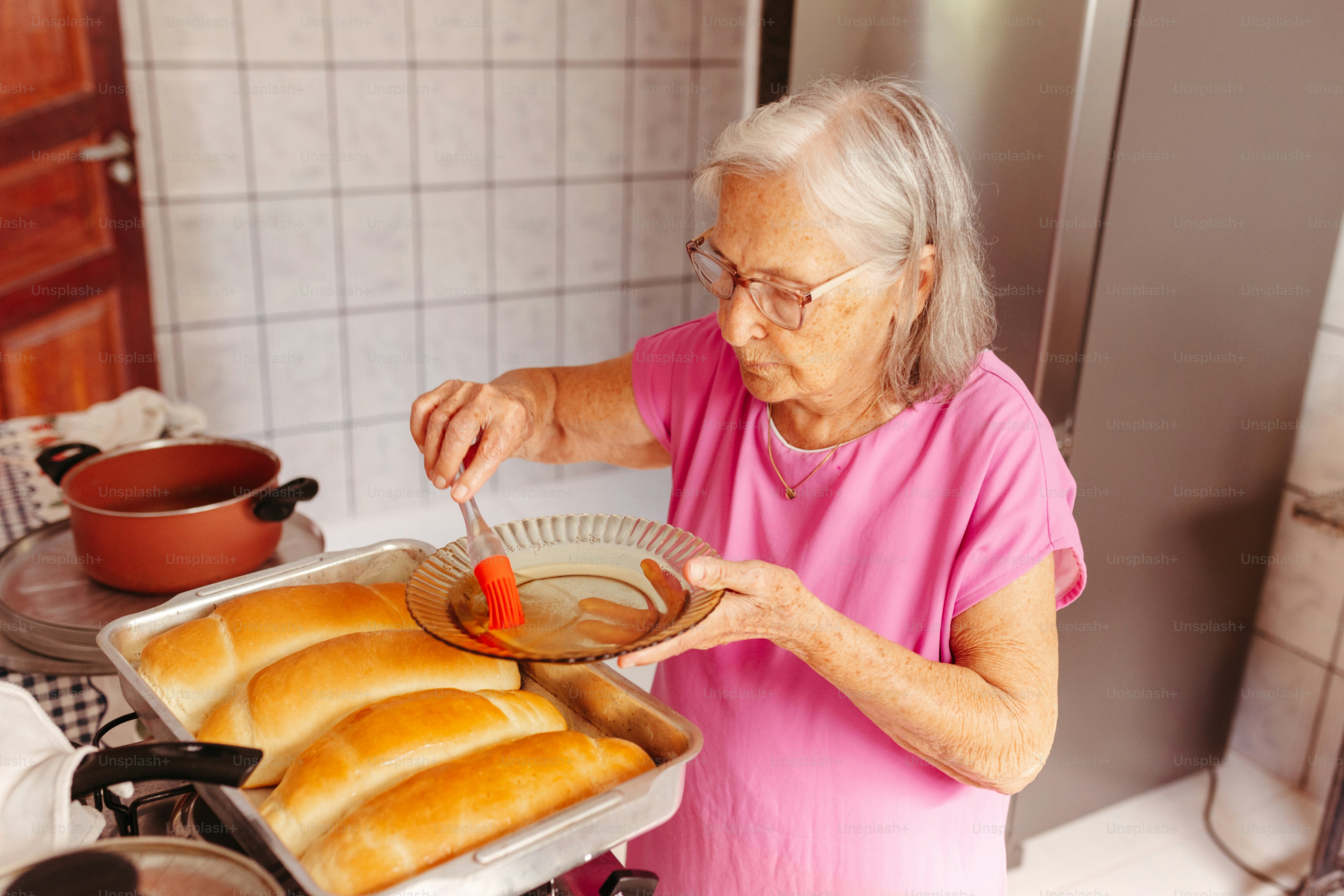 a woman in a pink shirt is putting something in a pan