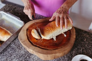 una persona cortando una barra de pan en una tabla de cortar