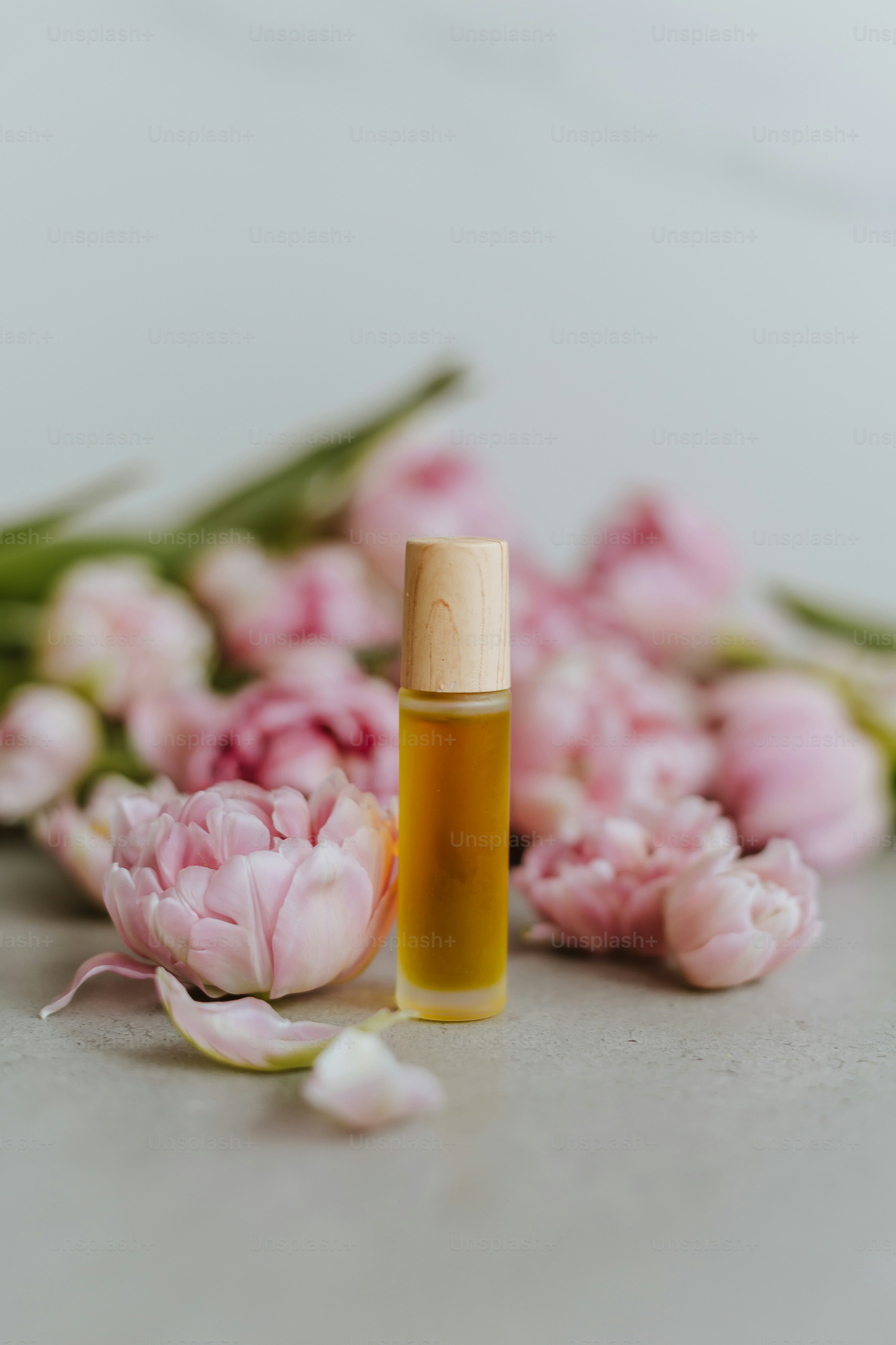 a bottle of essential oil next to a bunch of flowers