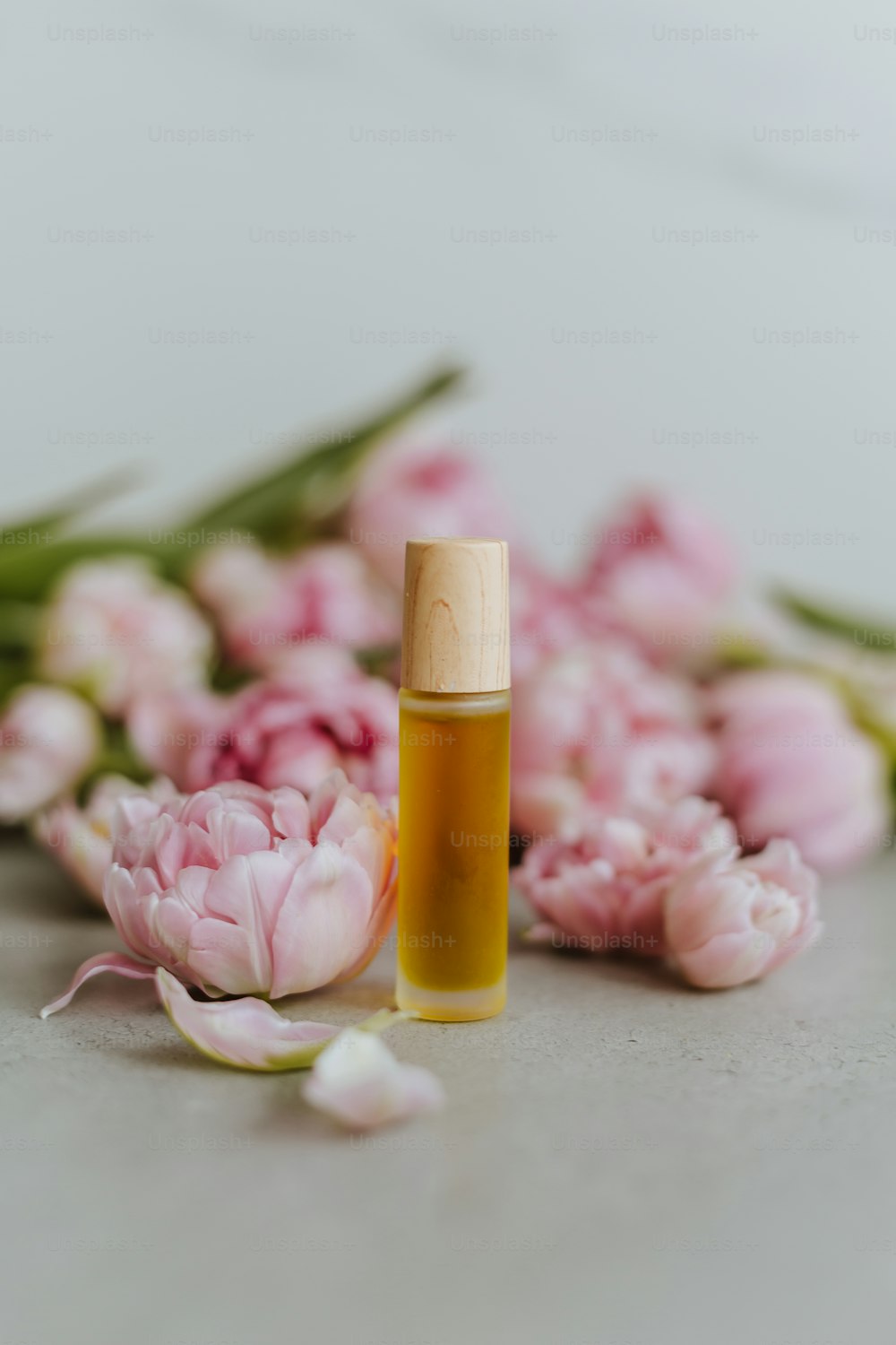 a bottle of essential oil next to a bunch of flowers