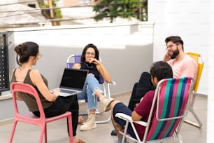 a group of people sitting around a table with laptops